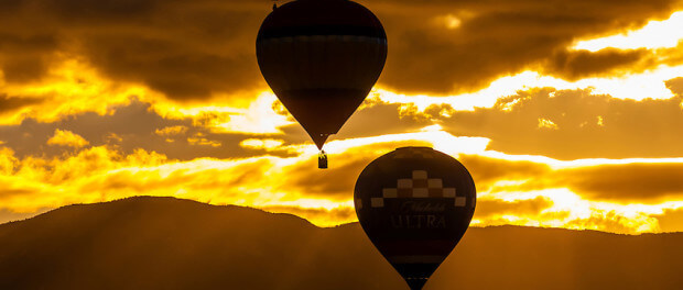 Hot air balloons flying at sunrise (with the Sandia Mountains in the background), Albuquerque International Balloon Fiesta, Albuquerque, New Mexico USA.